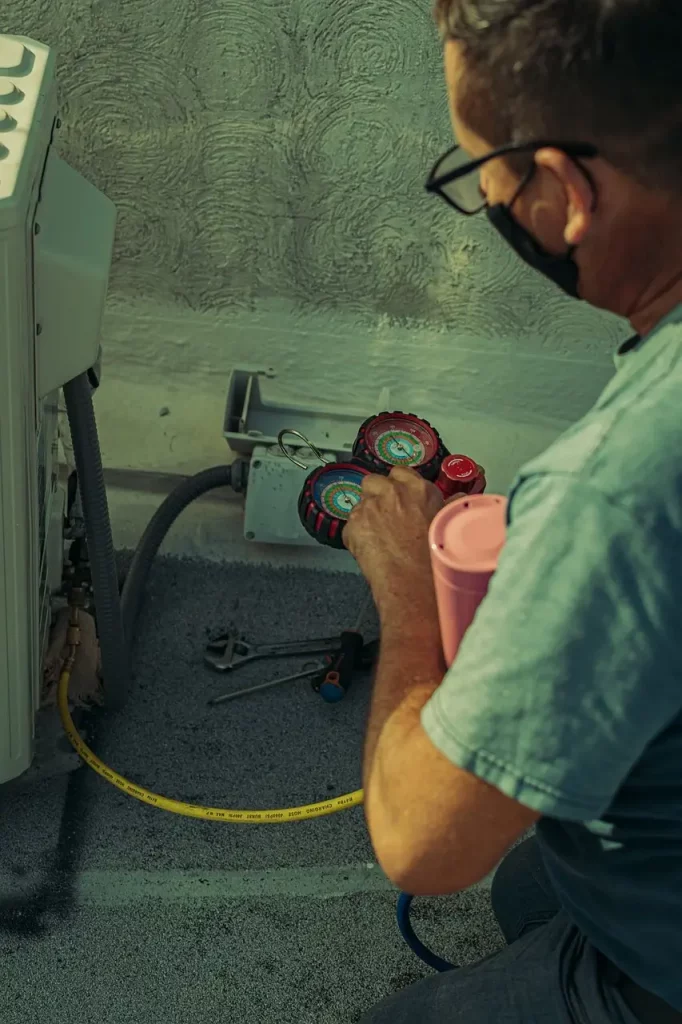 Technicien réparant un climatiseur mural en panne.